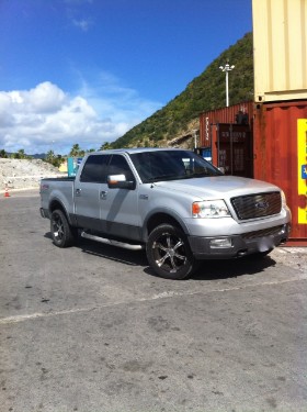 Auf dem Parkplatzareal am Flughafen Sint Maarten treten die Zielpersonen Händchen haltend laufend an einen amerikanischen Pick-Up-Truck heran. Bildrechte: DSD Detektiv SYSTEM Detektei ® GmbH / Randel 